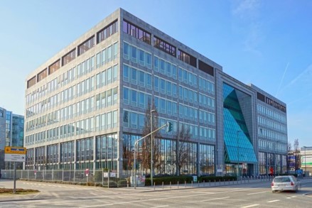 Modernes Bürogebäude mit großer Glasfassade an einer Straßenecke im Stadtteil Kaiserlei in Offenbach am Main, bei sonnigem Wetter aufgenommen.